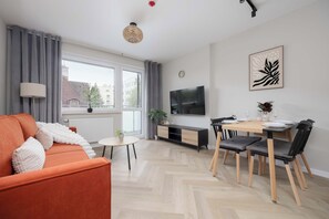 Un salon moderne avec un canapé, une table à manger et un téléviseur.