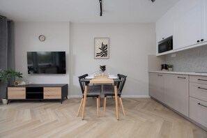 Une cuisine moderne avec un coin repas, un plancher en bois et un téléviseur à écran plat fixé au mur.