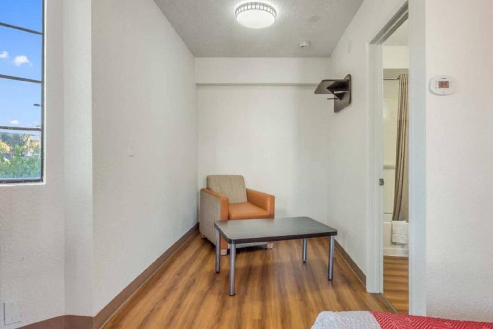 A narrow hallway with a wooden floor, a single chair, and a small table.