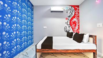 Una camera da letto con un letto, una parete decorata con un motivo floreale, un condizionatore d'aria e una parete con un design rosso e nero.