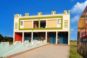 A two-story building with a flat roof, a central entrance, and a paved driveway leading to the entrance.