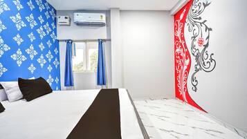 A hotel room with a bed, a window with curtains, an air conditioning unit, and a decorative wall.