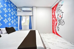 Habitación de hotel con cama, ventana con cortinas, unidad de aire acondicionado y un adorno en la pared.