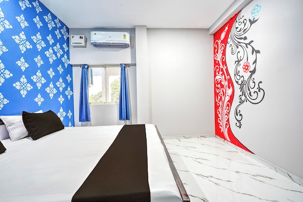 A hotel room with a bed, a window with curtains, an air conditioning unit, and a decorative wall. - Hotel O Pattamundai Formerly Jyoti Inn (Ali)