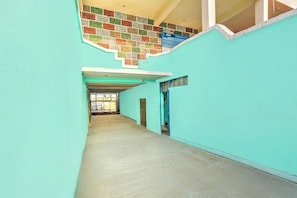 A narrow corridor with teal walls and a tiled ceiling.