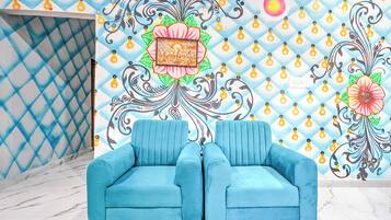 A room with a blue sofa, a patterned wall, and a diamond-patterned area.