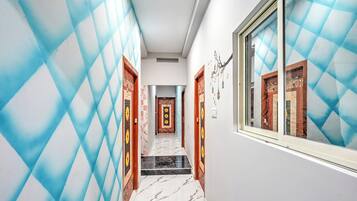 A hallway with patterned walls, a tiled floor, and doors with traditional designs.