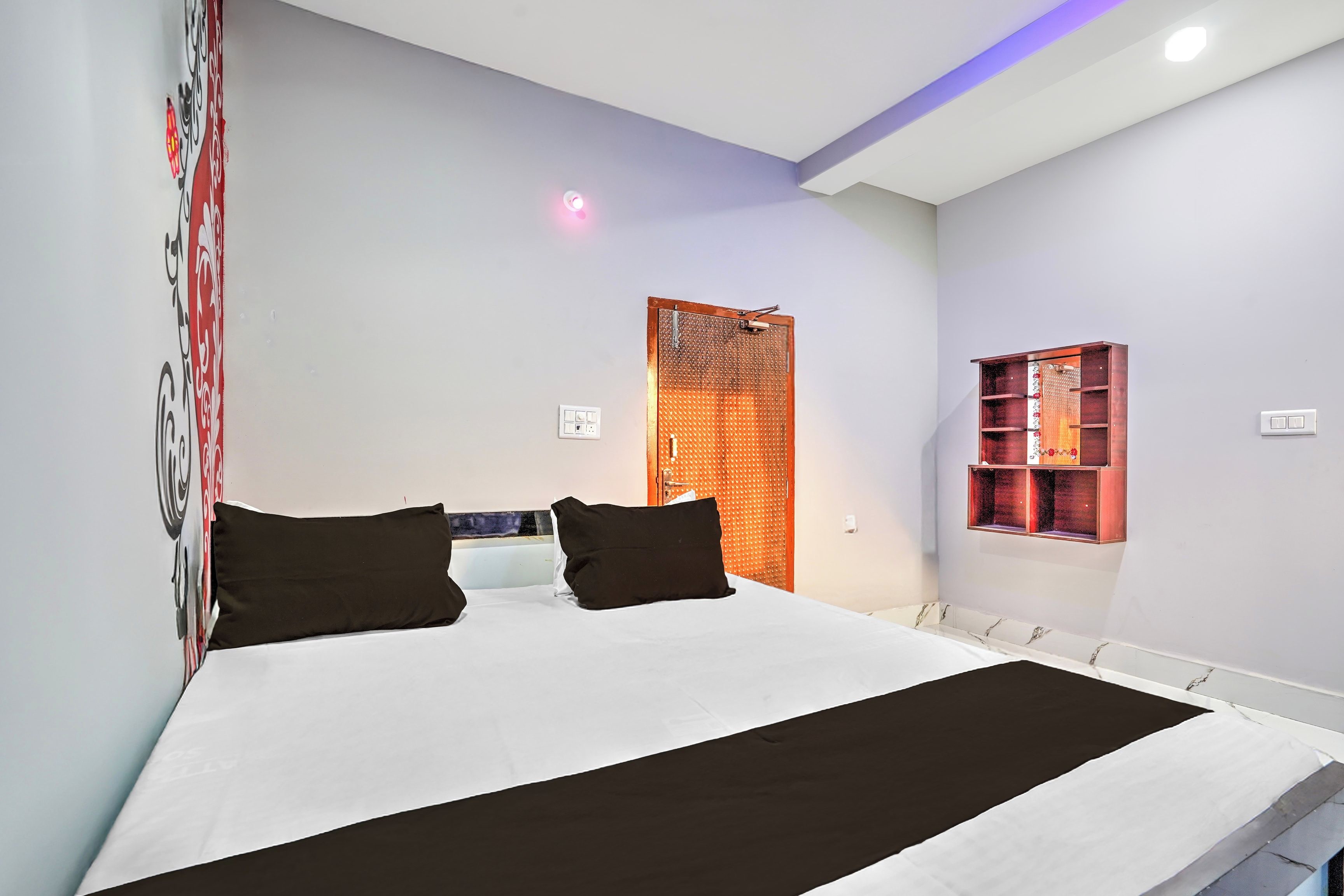 Une chambre moderne avec un grand lit, une petite fenêtre et un panneau mural décoratif.