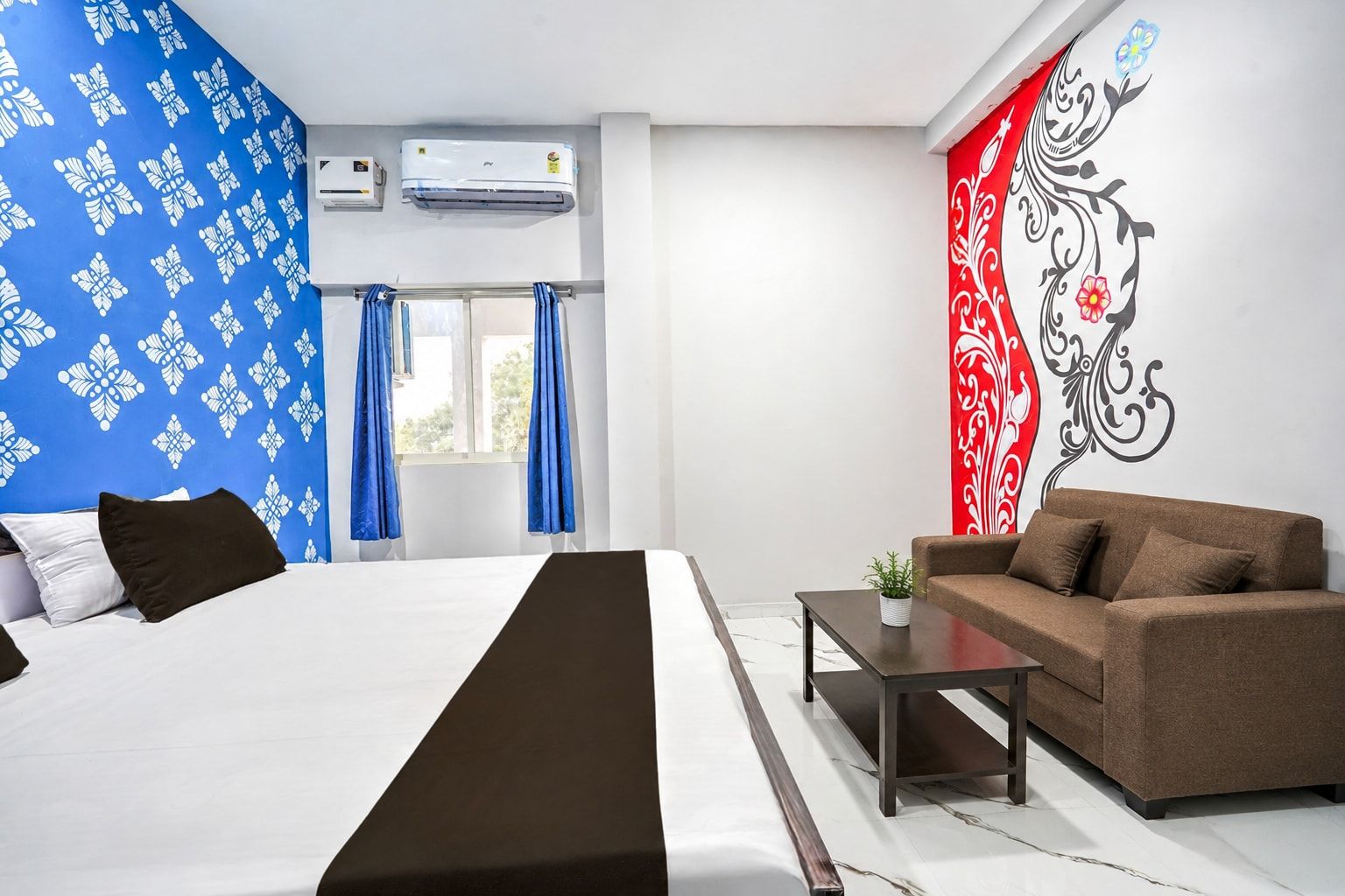 Habitación de hotel con cama, sofá, mesita de café y decoración en la pared.
