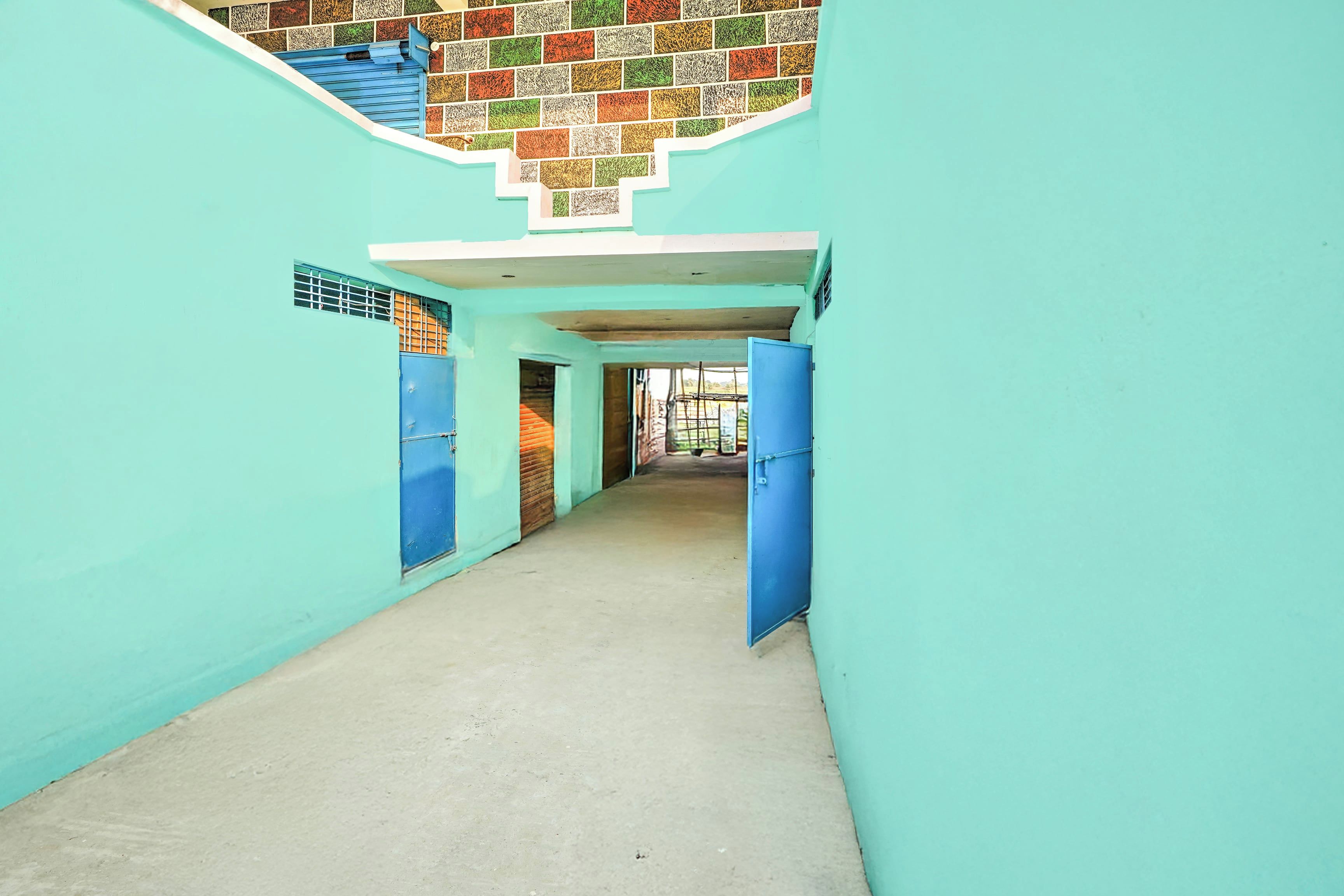 A corridor with blue doors, a tiled wall, and a concrete floor.