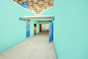 A corridor with blue doors, a tiled wall, and a concrete floor.