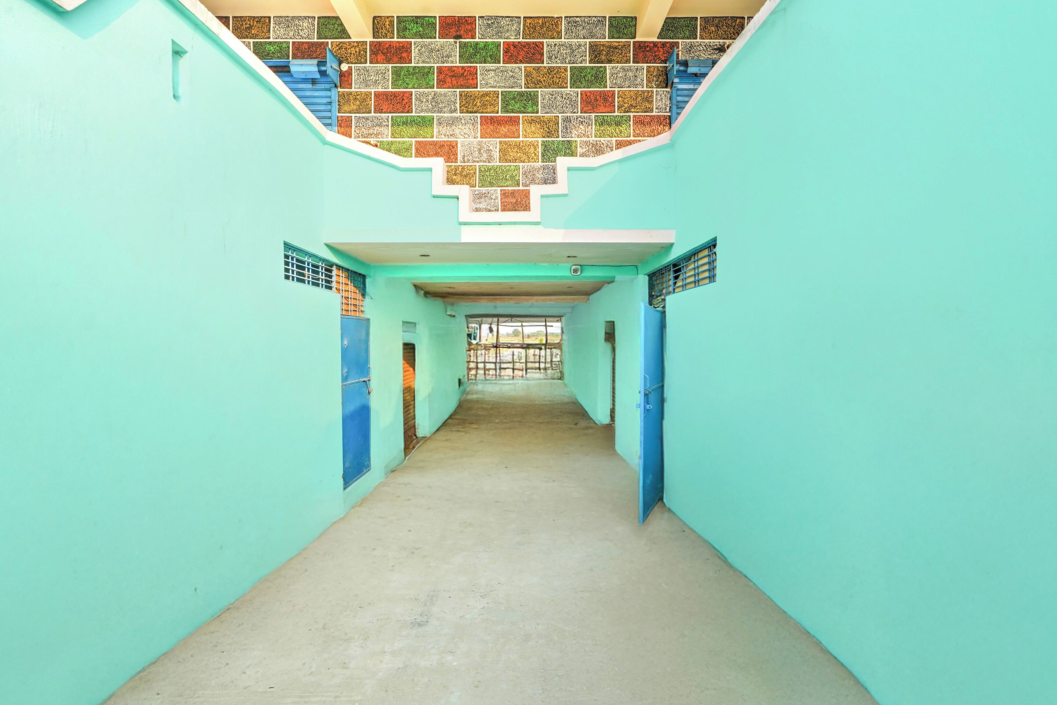 Un couloir avec un mur recouvert de carreaux et des portes bleues.
