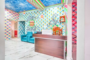 A vibrant room with a patterned wall, a blue sofa, and a wooden reception desk.