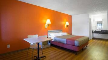 A hotel room with a bed, a desk, and two wall-mounted lamps.