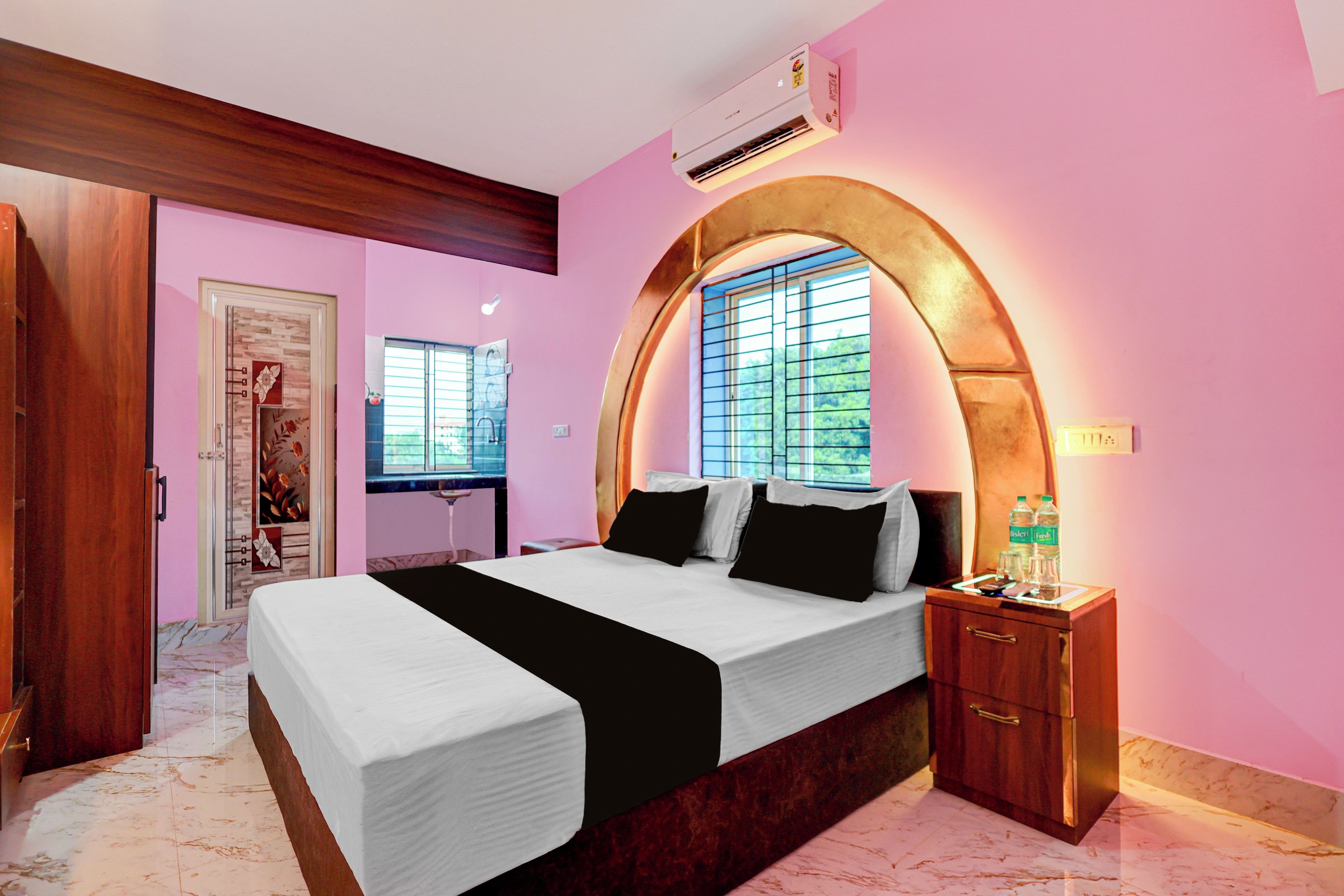 A bedroom with a bed, a nightstand, an arched window, and a door.