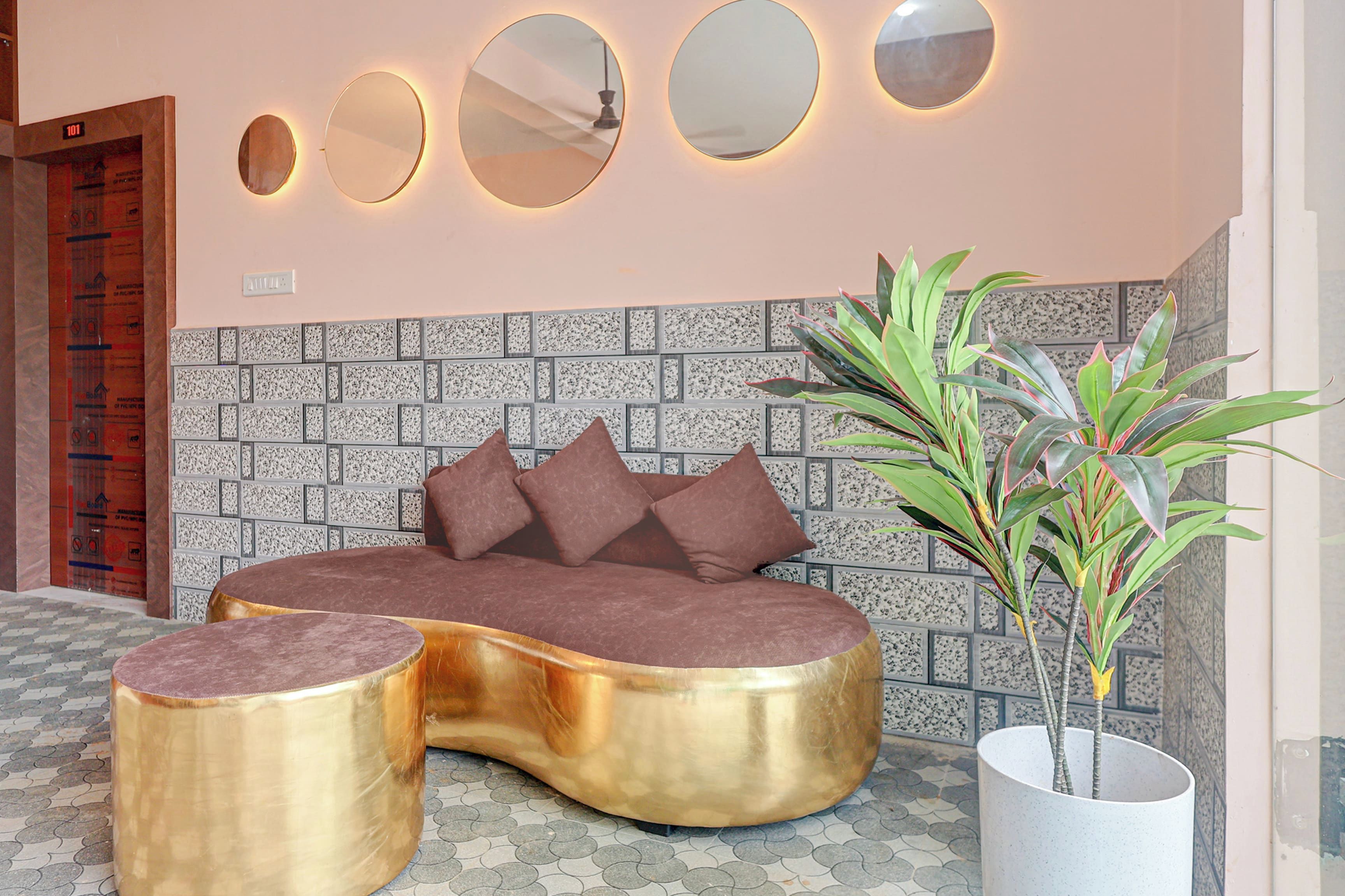 Una habitación moderna con un sofá curvo, una planta en maceta y una pared con un diseño único de azulejos.