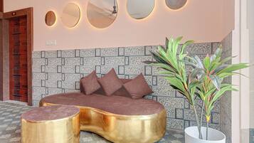 Una habitación moderna con un sofá curvo, una planta en maceta y una pared con un diseño único de azulejos.