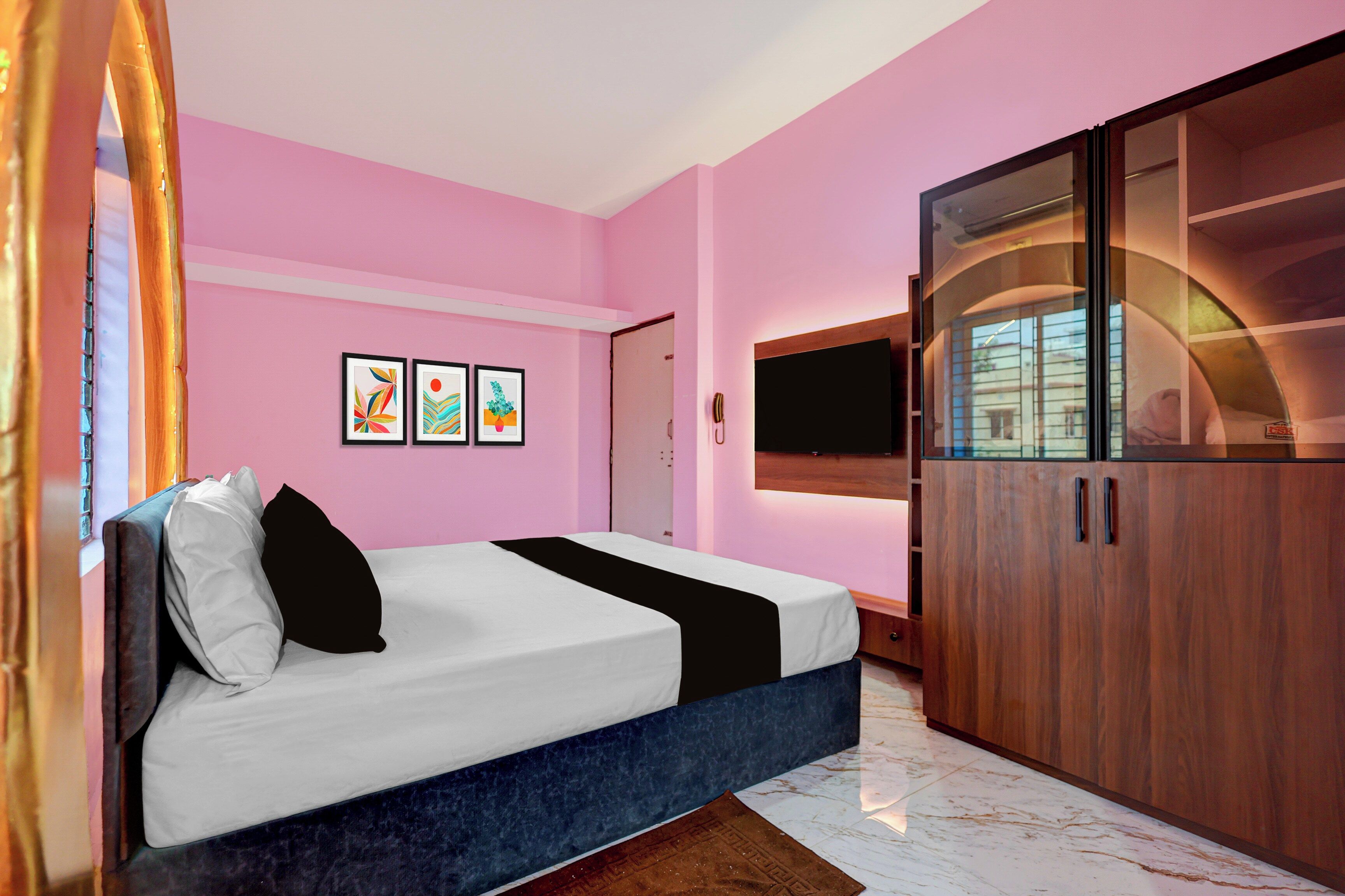 Un dormitorio con cama, armario, televisor de pantalla plana y obras de arte en la pared.