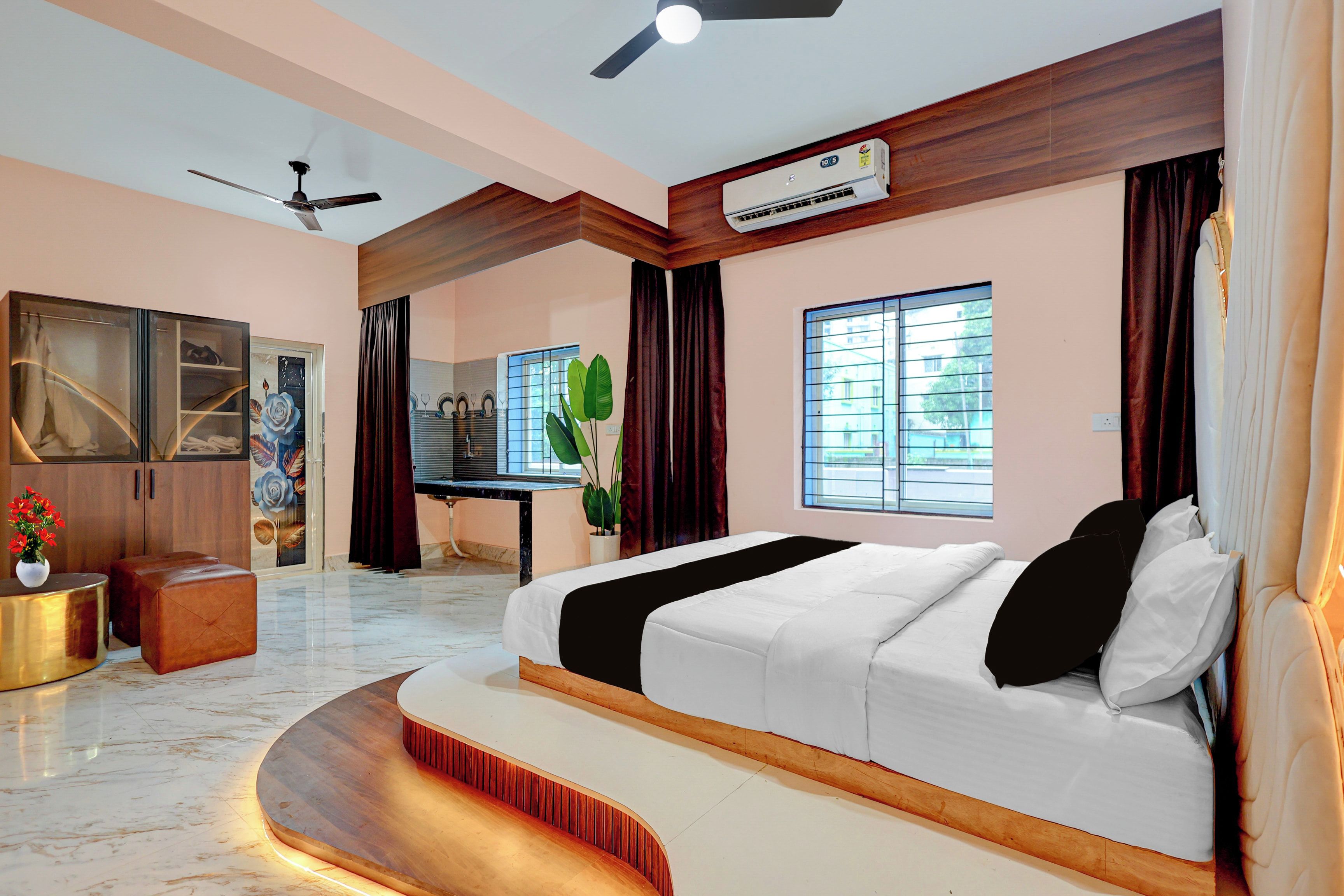 Une chambre moderne avec un grand lit, un ventilateur de plafond, un appareil de climatisation, une coiffeuse avec un miroir et une fenêtre avec des stores.
