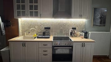 A kitchen with white cabinets, a double sink, a stove, and a microwave.