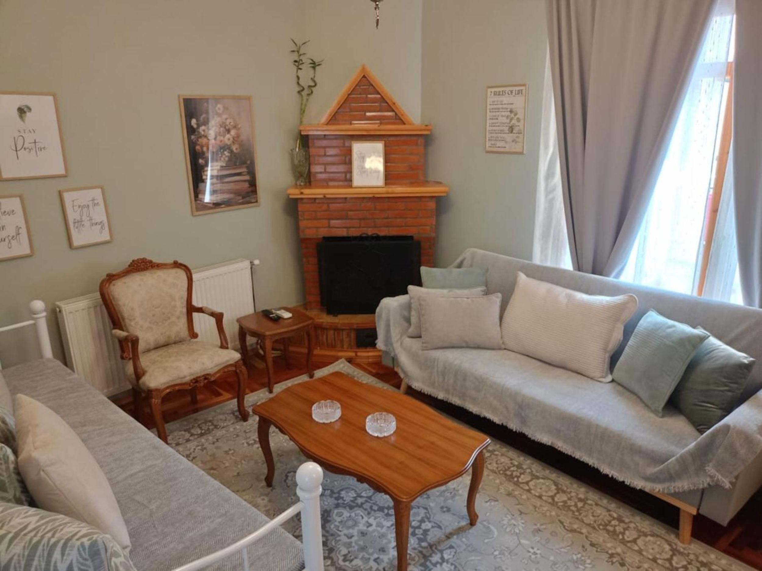 Een woonkamer met een open haard, een bank, een stoel en een salontafel.