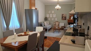 Un espacio habitable compacto con comedor, kitchenette y área de descanso con sofá y sillones.