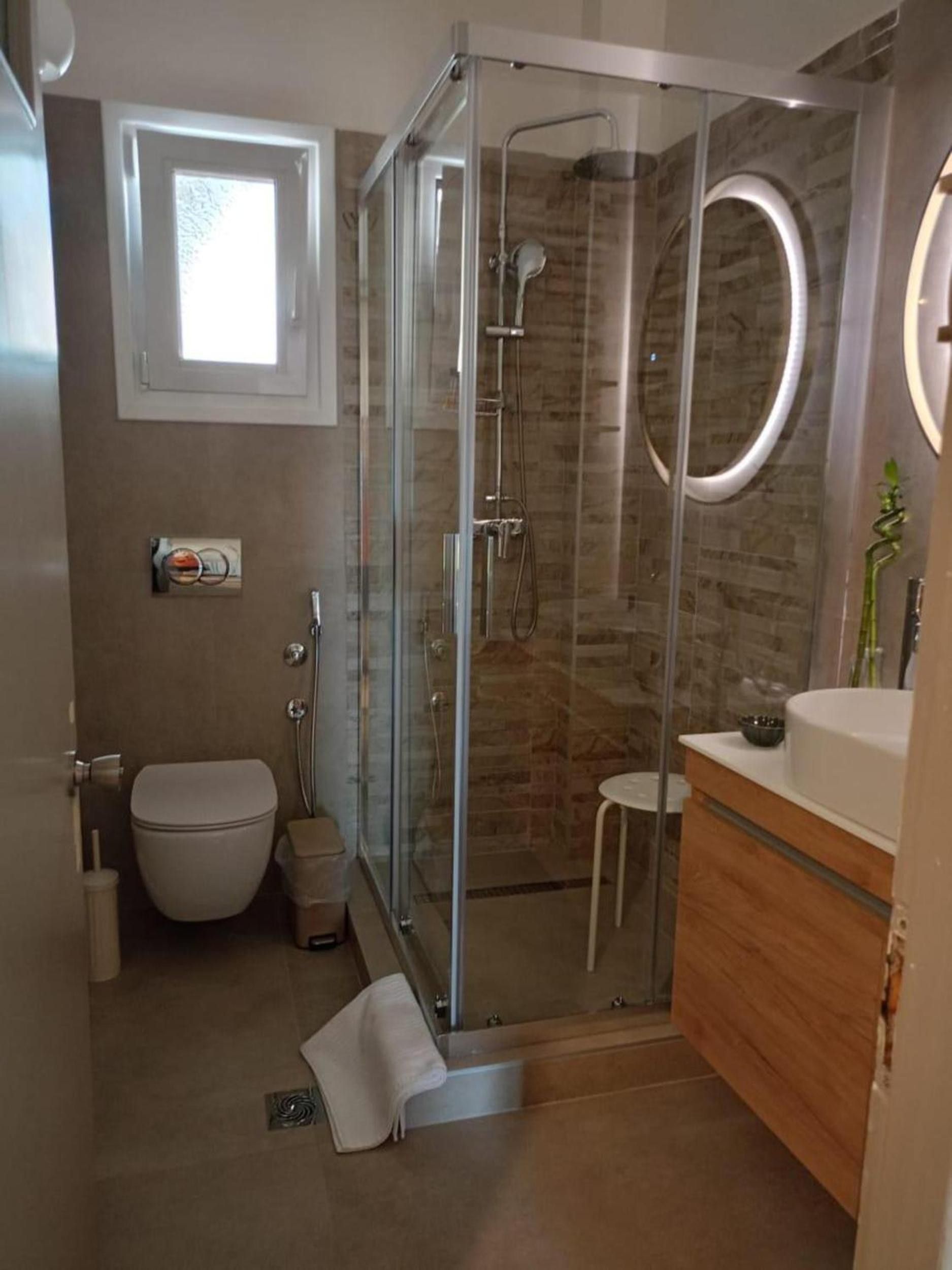 Een moderne badkamer met een douche met glazen wand, een toilet en een wastafel met spiegel.