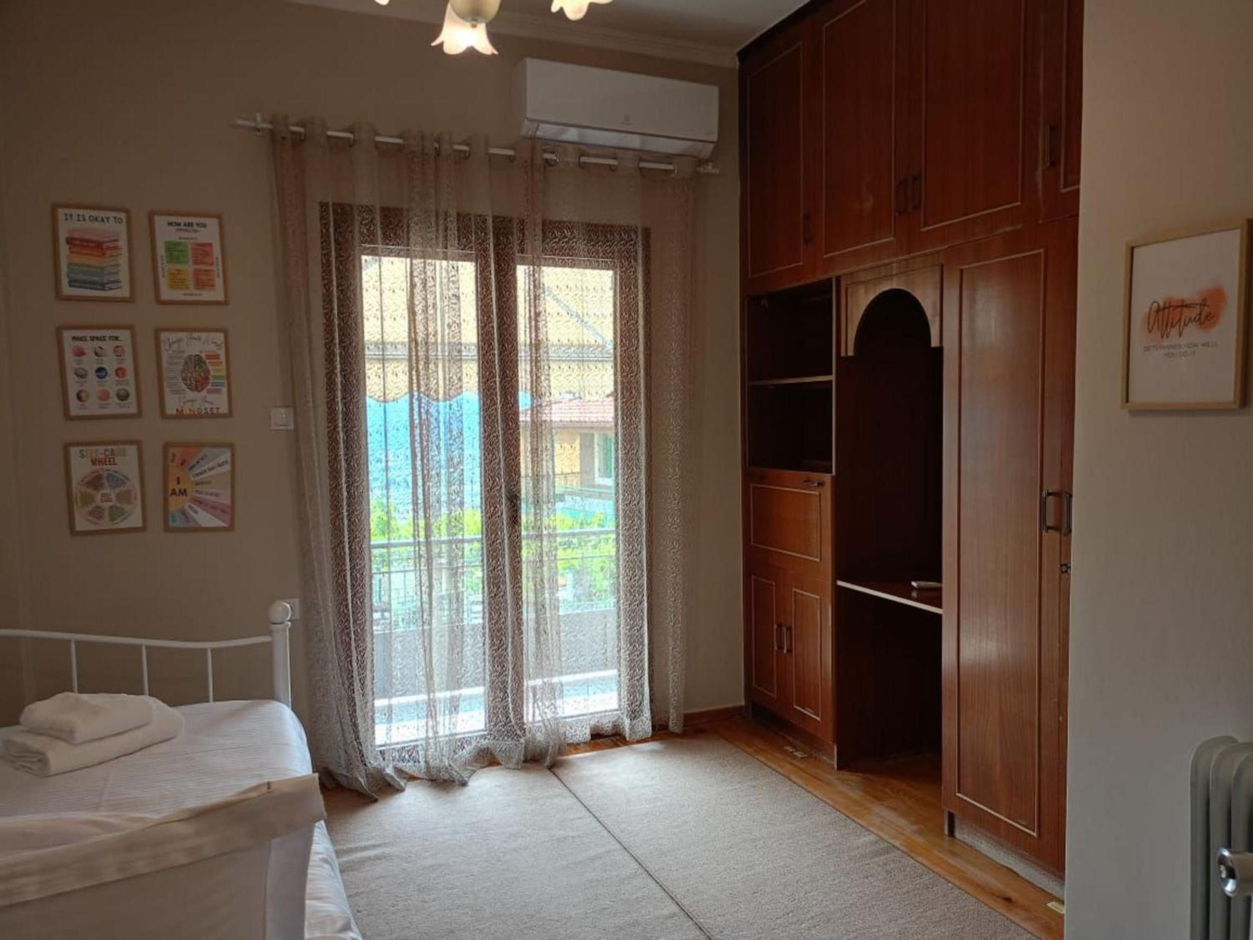 A bedroom with a bed, a wardrobe, a radiator, and a window with curtains.