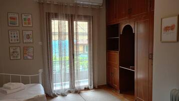 A bedroom with a bed, a wardrobe, a radiator, and a window with curtains.