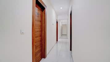 A corridor with wooden doors, white walls, and a tiled floor.