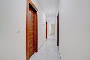 Un pasillo con puertas de madera, paredes blancas y piso de baldosas.