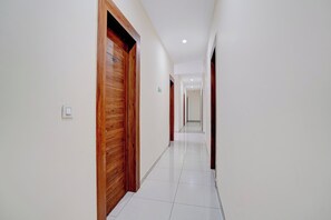 A corridor with wooden doors, white walls, and a tiled floor.