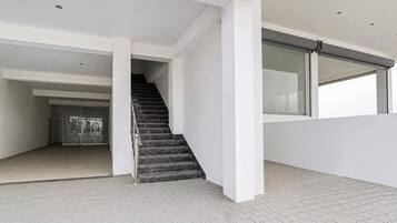 Un interior moderno con una escalera, paredes blancas y piso de baldosas.