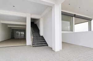 Un interior moderno con una escalera, paredes blancas y piso de baldosas.