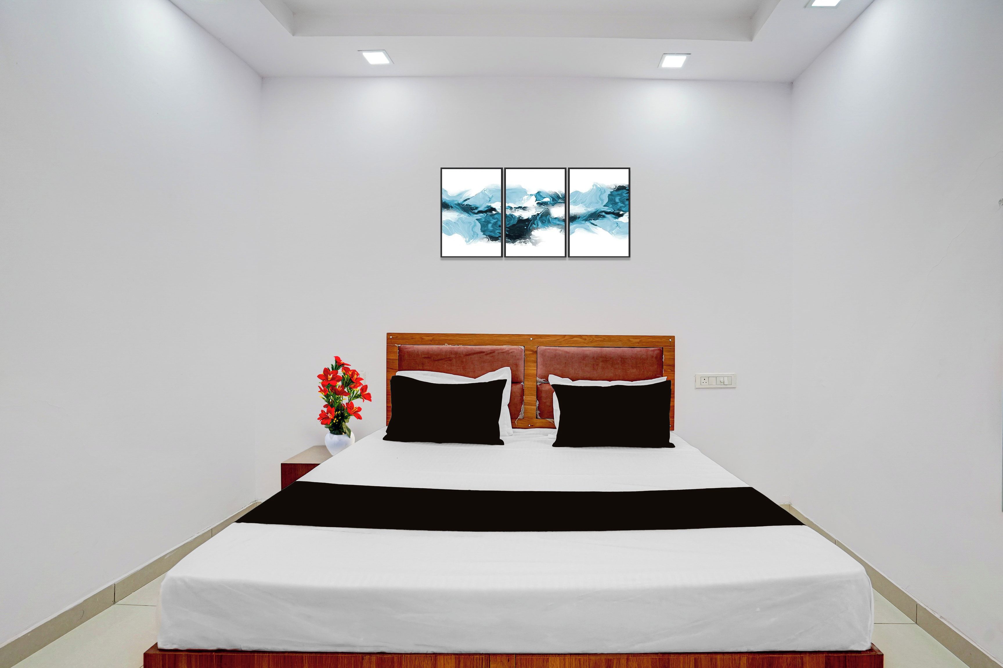 Un dormitorio moderno con una cama grande, un cabecero de madera y una mesita de noche con un jarrón de flores.