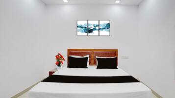 Un dormitorio moderno con una cama grande, un cabecero de madera y una mesita de noche con un jarrón de flores.