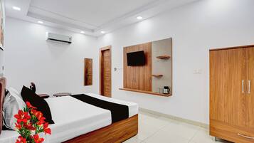 A modern bedroom with a bed, wooden wardrobe, a mounted TV, and an air conditioning unit.