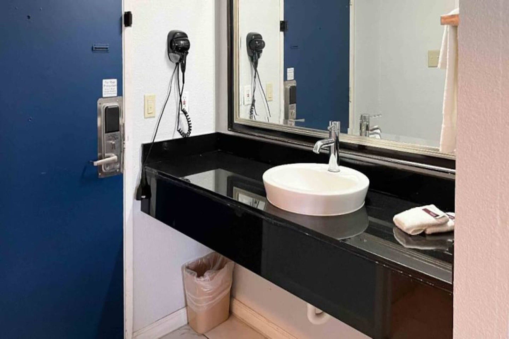 A bathroom with a black countertop, a white sink, and a mirror.