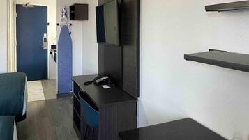 Ein Hotelzimmer mit Schreibtisch, Stuhl, Fernseher und einem kleinen Tisch.