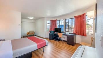 Habitación de hotel con dos camas, un escritorio, una silla y un televisor.