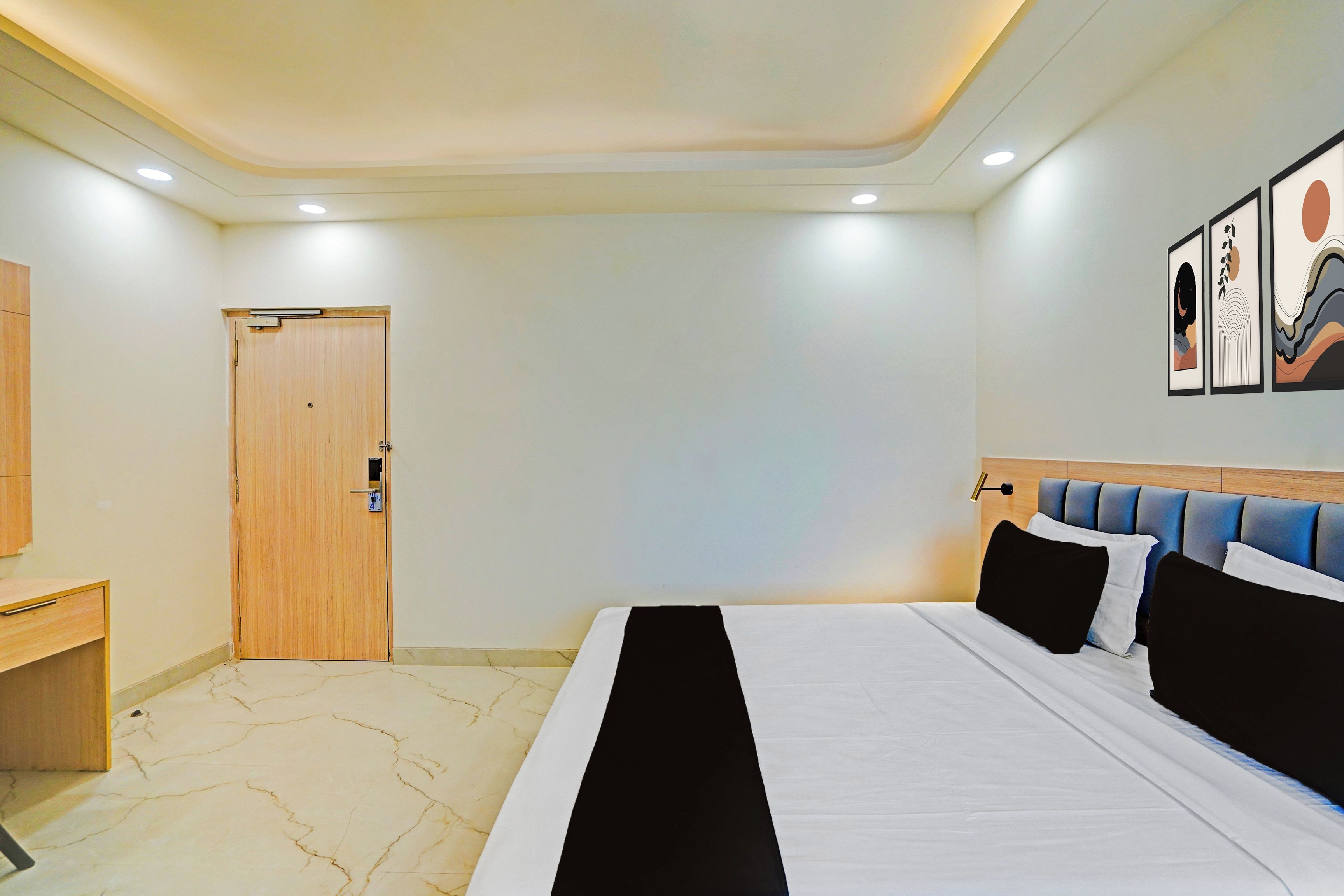 Una habitación de hotel con cama, escritorio, puerta y decoración en la pared.
