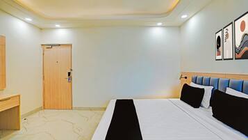 Una habitación de hotel con cama, escritorio, puerta y decoración en la pared.