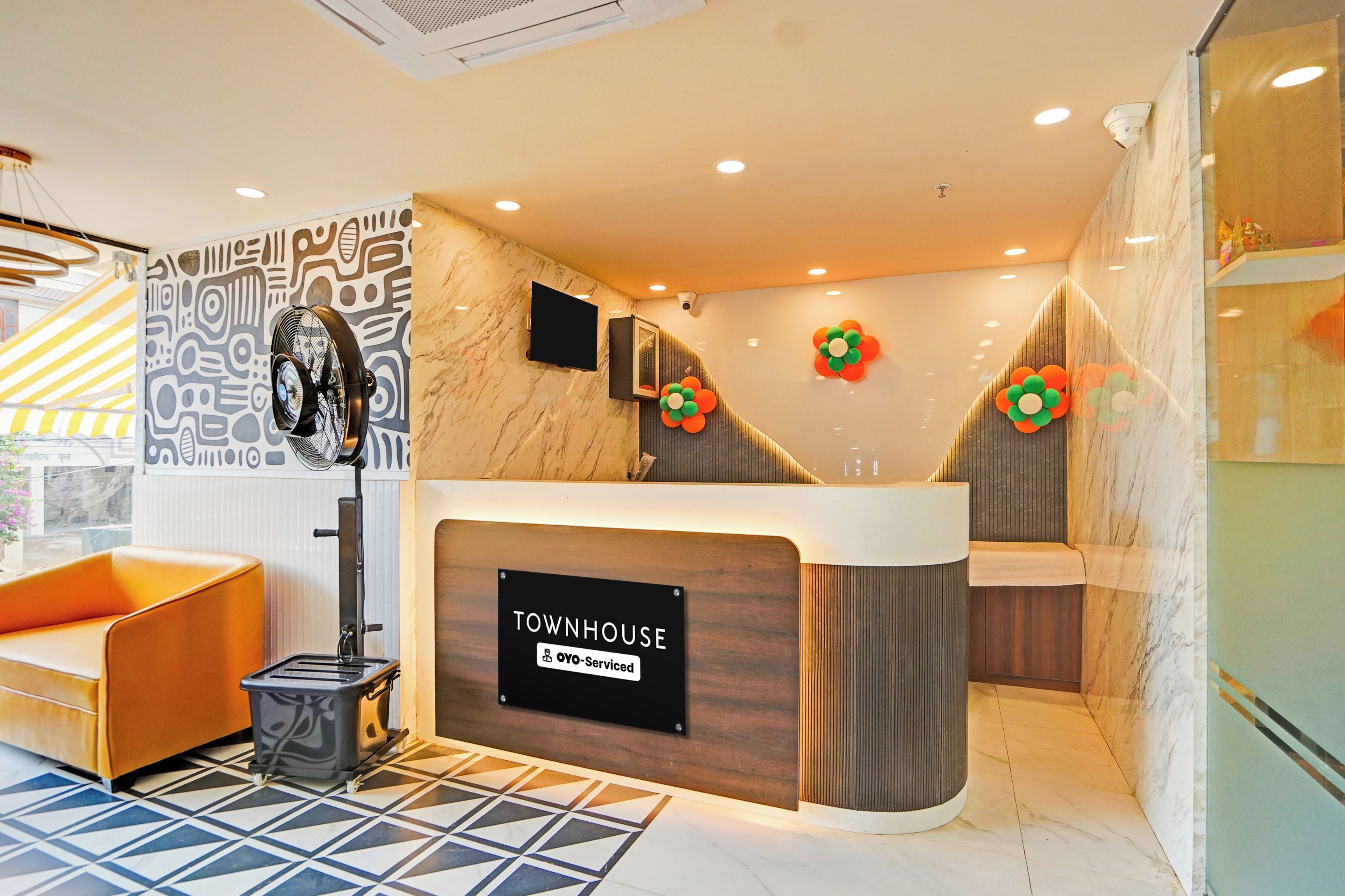 A reception desk with a sign reading 'TOWNHOUSE' and a modern interior design with a patterned wall and a tiled floor.