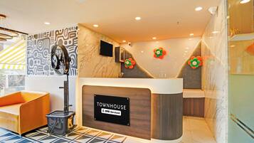 A reception desk with a sign reading 'TOWNHOUSE' and a modern interior design with a patterned wall and a tiled floor.