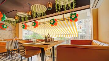 L’intérieur d’un restaurant, avec une marquise à rayures, des plantes suspendues et une vue sur l’extérieur.