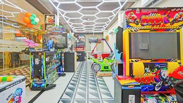 Un salón de juegos muy iluminado con diversas máquinas recreativas y decoraciones coloridas.