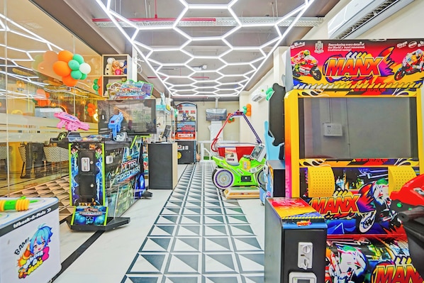 Un salón de juegos muy iluminado con diversas máquinas recreativas y decoraciones coloridas.