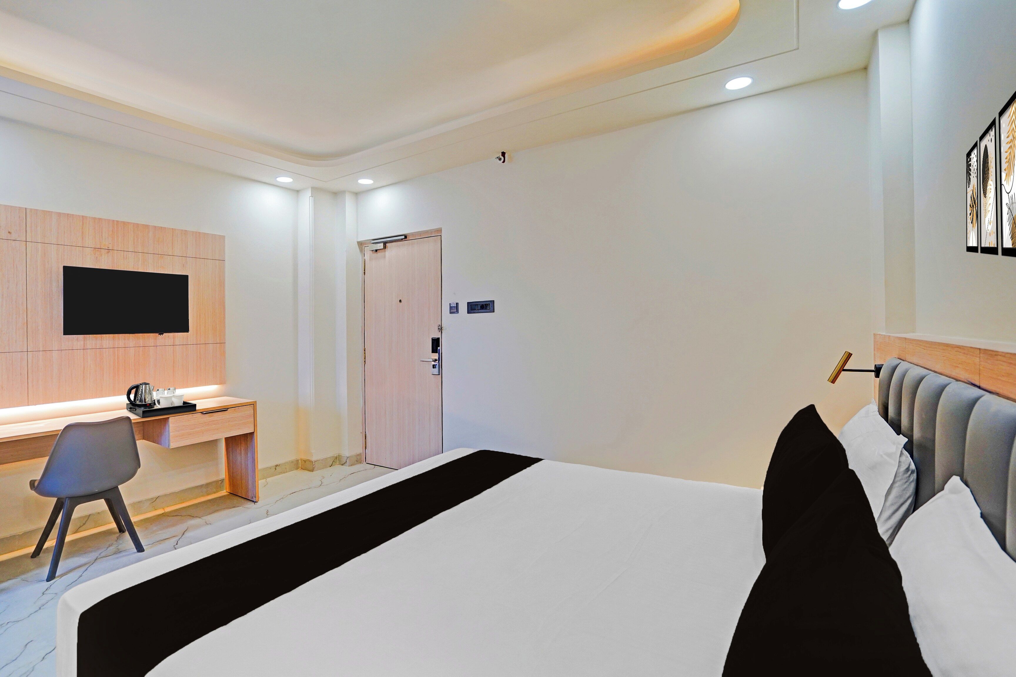 A hotel room with a bed, a desk, a chair, a television, and a door.