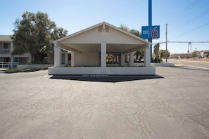 A building with a covered parking area and a sign indicating '6' for entry.