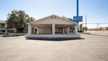 A motel with a covered entrance, a 'No Parking' sign, and a '6' sign indicating the entrance.